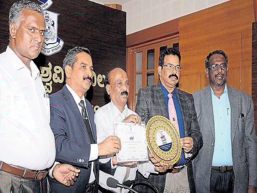 In-charge Vice-Chancellor of University of Mysore (UoM) Dayananda Mane shows the award conferred upon UoM&#8200;by the Union HRD&#8200;ministry at Crawford Hall in Mysuru on Thursday. Director for Planning, Monitoring and Evaluation Board and Nodal Officer for Ranking Lingaraj Gandhi, UoM Registrar R&#8200;Rajanna, Registrar (Evaluation) J&#8200;Somashekar and Finance  Officer Mahadevappa are also seen. DH photo