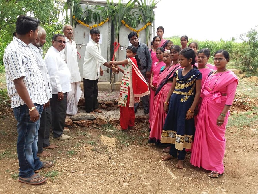A girl ties rakhi to her brother in front of the toilet gifted by him on the occasion of Rakshabandhan at a village in Belagavi district on Sunday. DH Photo 