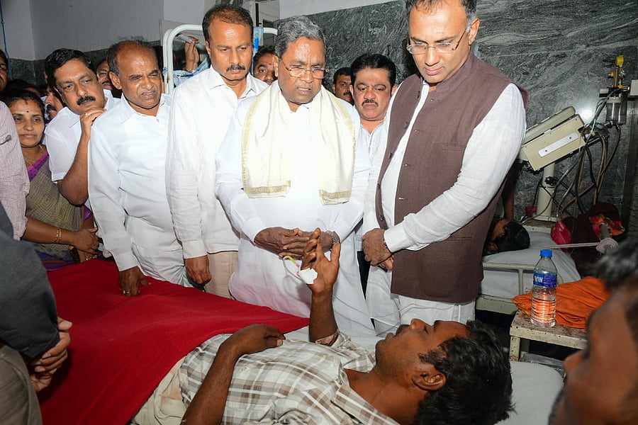 Former chief minister Siddaramaiah inspects the well being of the victims of Sulvadi temple prasadam poison case, at K R Hospital, in Mysuru, on Saturday. Karnataka Pradesh Congress Committee President Dinesh Gundu Rao, MP R Dhruvanarayan, Minister C Puttarangashtty are seen. DH File Photo