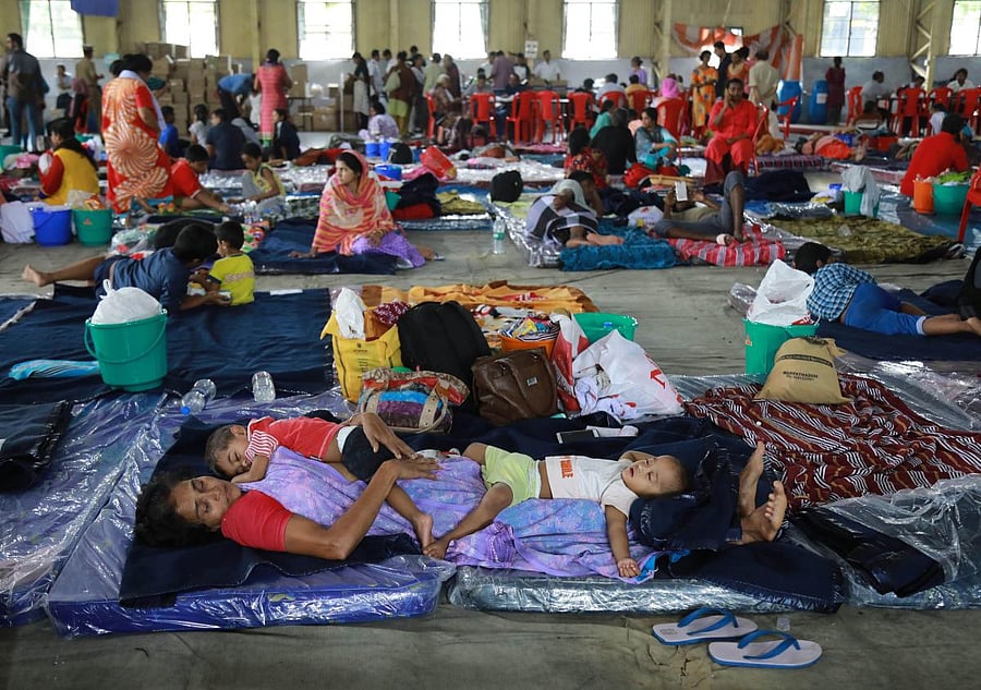 An woman rescued by Navy personnel rests with her grandchildren at the Naval relief camp in Kochi. (AFP Photo)