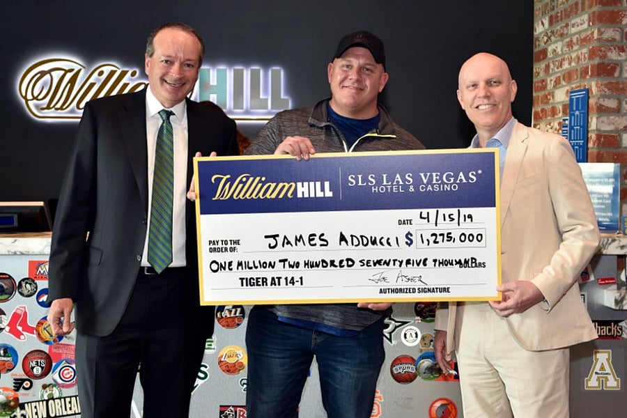 A delighted James Adducci (centre) picks up the $1.275 million from bookmaker William Hill after successfully tipping Tiger Woods to win the Masters.