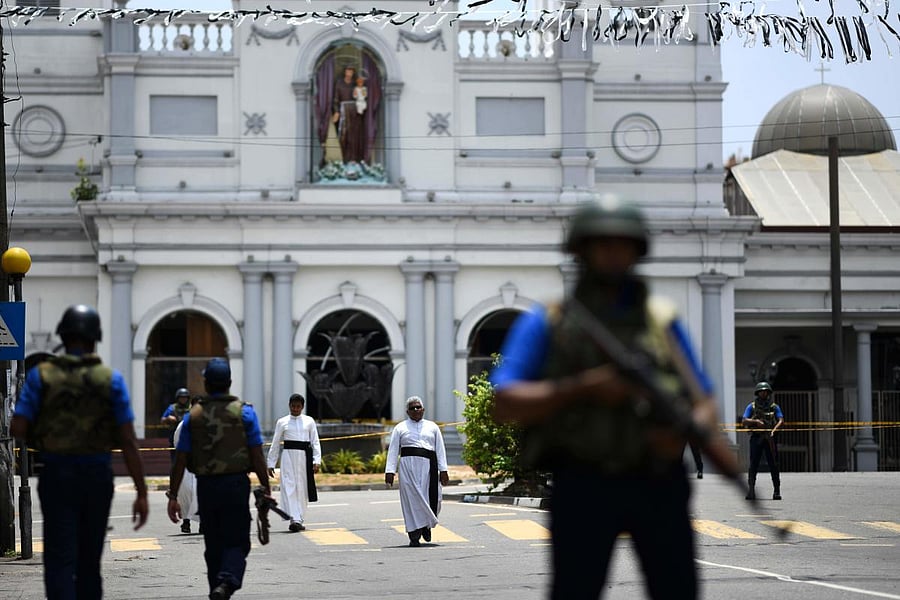 Priests walk on a blocked street as soldiers stand guard outside St. Anthony's Shrine in Colombo on April 25, 2019, following a series of bomb blasts targeting churches and luxury hotels on the Easter Sunday in Sri Lanka. - All of Sri Lanka's Catholic chu