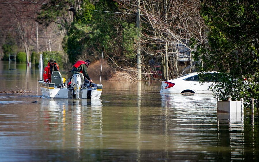 Canadian police drift past a car partially submerged in water on a flooded street in Sainte-Marthe-sur-le-Lac in the suburbs of Montreal, Quebec, Canada. AFP