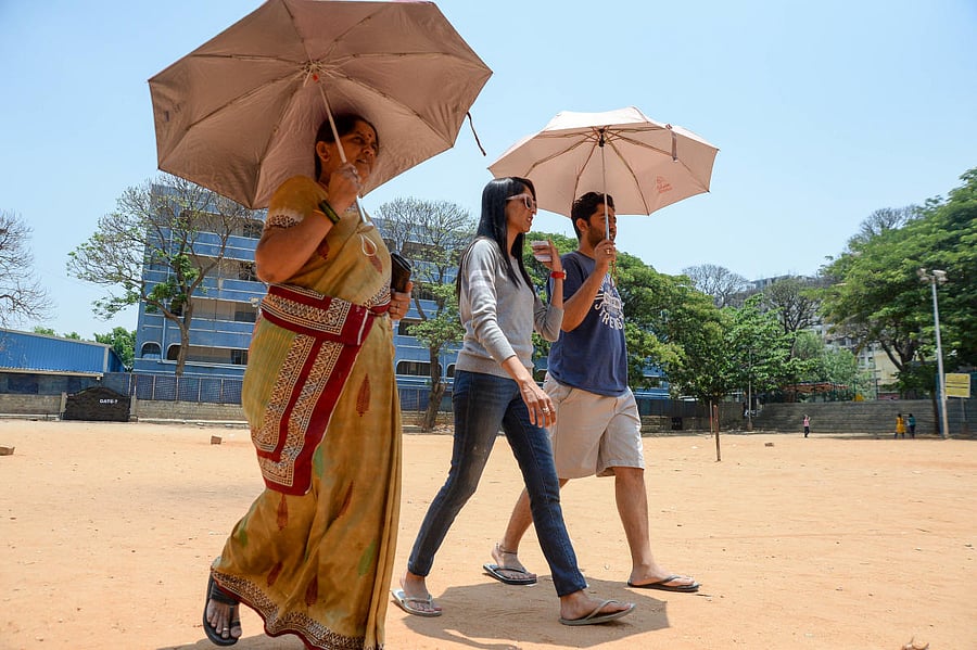 People carry umbrellas to take protection from the heat at a polling booth in Padmanabhanagar. DH photo/Satish Badiger