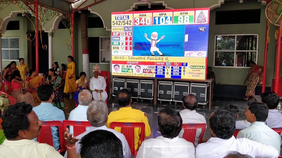 Relatives and friends watch the live telecast of Prime Minister Narendra Modi's victory on a huge LED screen along with a newlywed couple Sangamesh and Thanu in Hubballi on Thursday. DH Photo