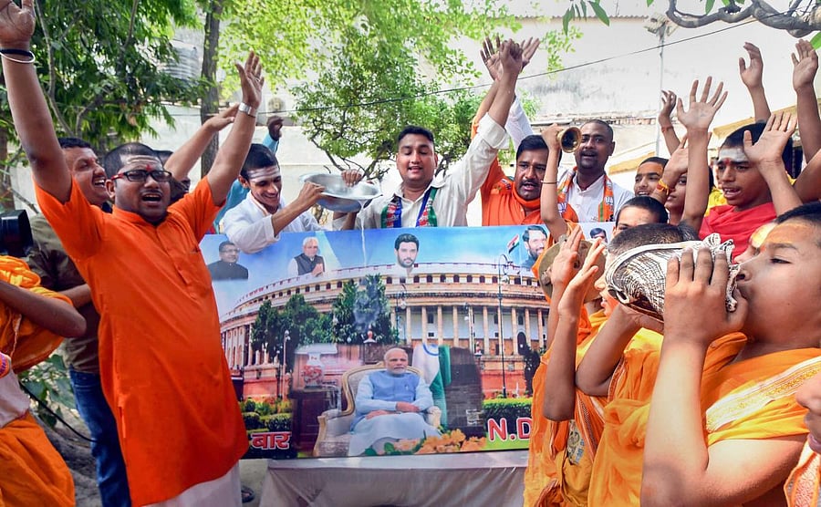 NDA supporters pour milk over a photo of Prime Minister Narendra Modi after their victory at Lok Sabha polls, in Patna, Friday, May 24, 2019. (PTI Photo)