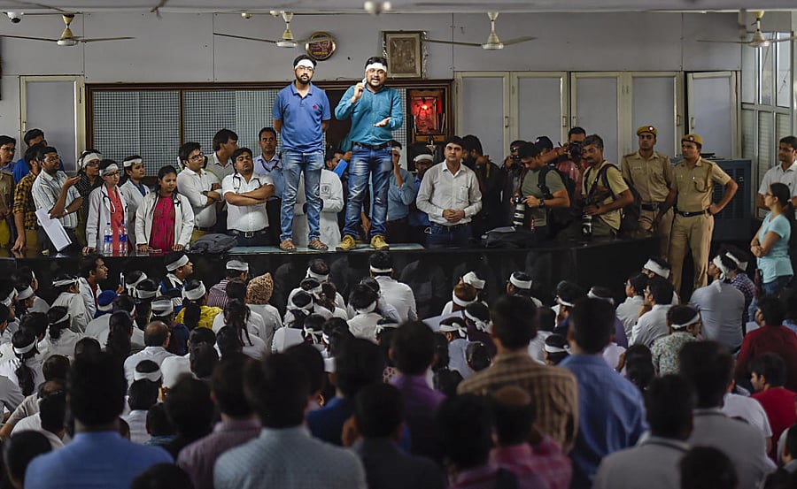 Members of Resident Doctors Association (RDA) of AIIMS wearing bandages on their heads protest to show solidarity with their counterparts in West Bengal, who stopped work on Tuesday protesting against the assault on their colleagues, in New Delhi, Friday,