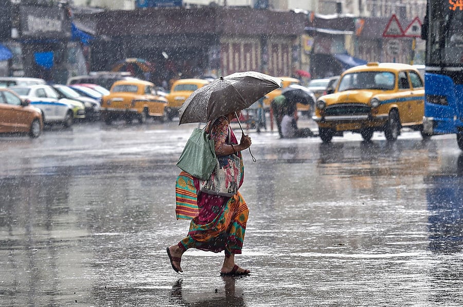 A pedestrian rushes to cross a busy city street during pre-monsoon rainfall, in Kolkata. PTI file photo