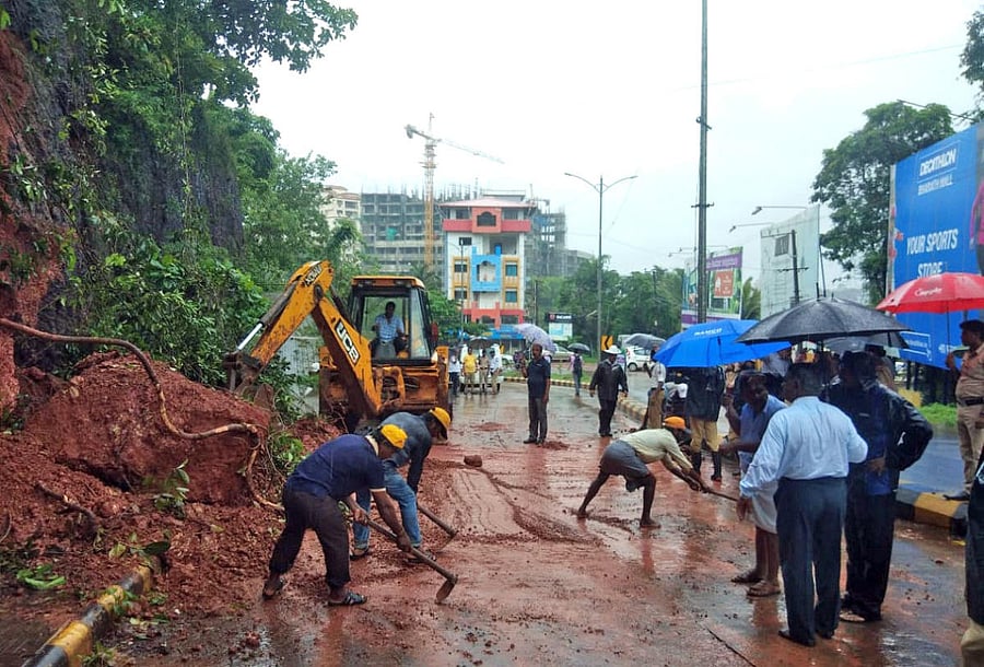 Labourers clear a boulder that fell due to heavy rain at Bejai Battagudda in Mangaluru on Monday.