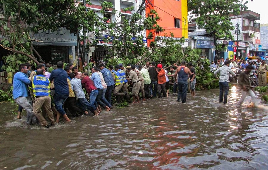 People remove an uprooted tree which had blocked a street, after a thunderstorm in Hyderabad on Thursday. PIT Photo