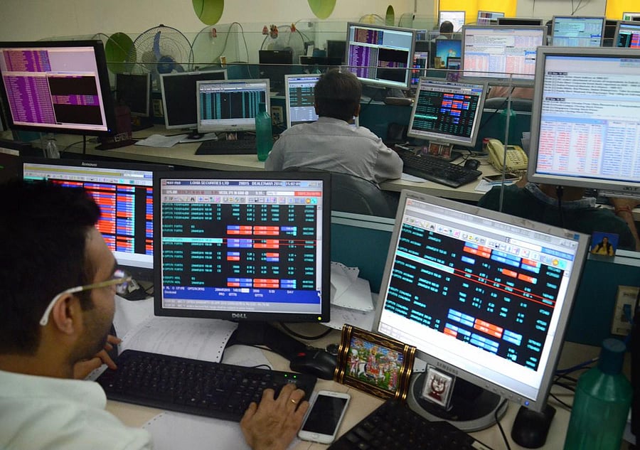 Sharebrokers and holders check the Sensex and Nifty at a share market in Kolkata on Friday. PTI File Photo