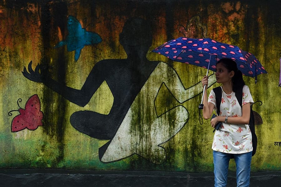 A student holds an umbrella as she waits for a bus outside a college during rain in Mumbai on August 2, 2019. AFP