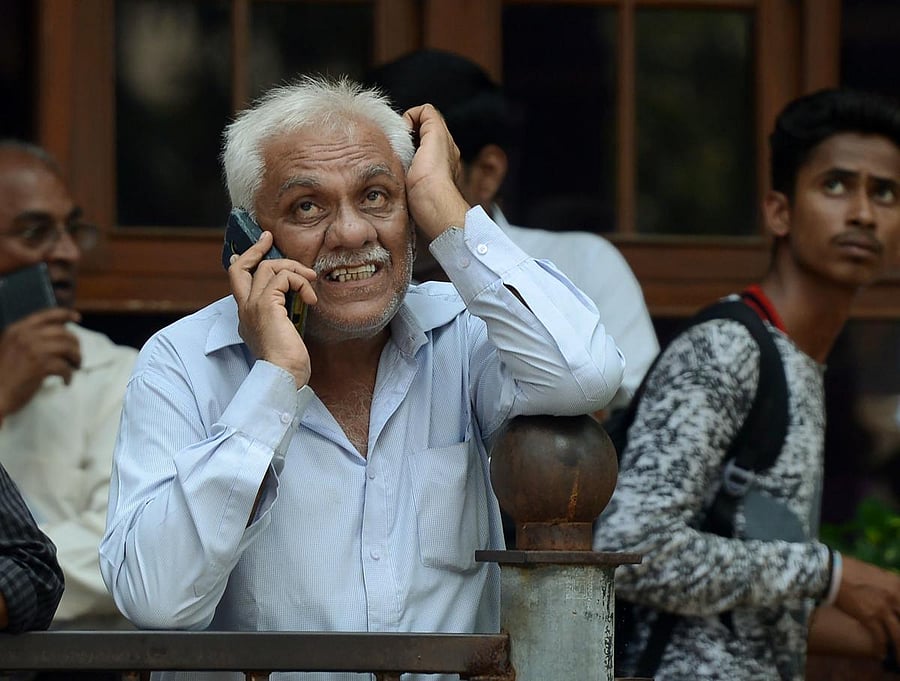 Investors watch movement of share prices on a digital broadcast outside the BSE in Mumbai. AFP FILE PHOTO