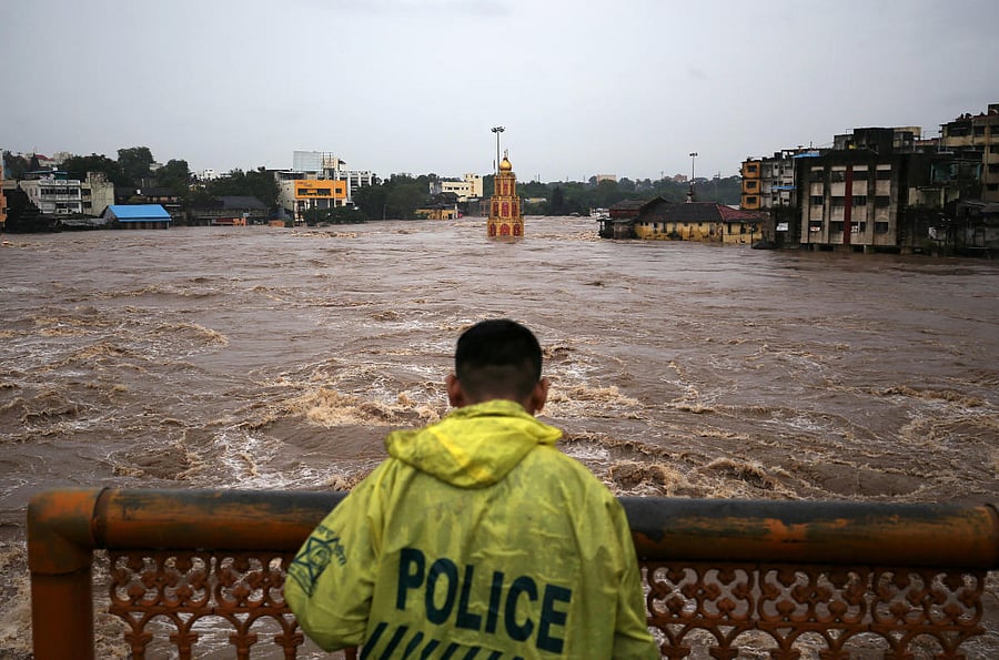 A policeman stands on a bridge as temples and houses are seen submerged in the waters of overflowing river Godavari after heavy rainfall in Nashik on August 4, 2019. (REUTERS)