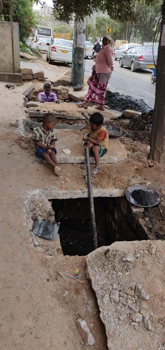Sanitary workers clean gutters in Hoodi without protective equipment, as children are left unattended.