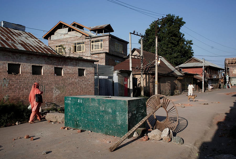 A Kashmiri woman walks past a blockade put up by residents to prevent security forces from entering their neighborhood during restrictions, in Srinagar. (Reuters Photo)