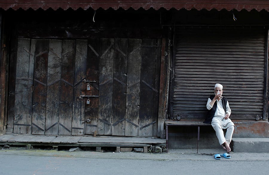 A Kashmiri man drinks tea as he sits outside closed shops. AFP file photo