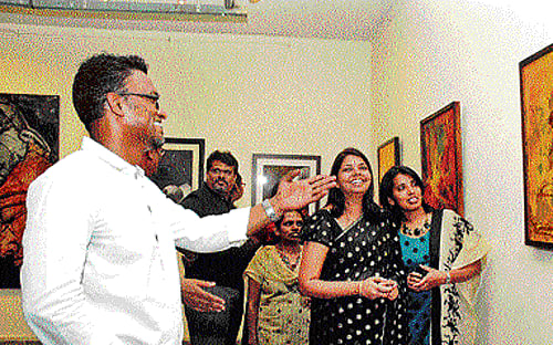 Artist Gurumahesh Srinivasan explains work to visitors at an exhibition at the Karnataka Chitrakala Parishath in the City on Wednesday. DH Photo