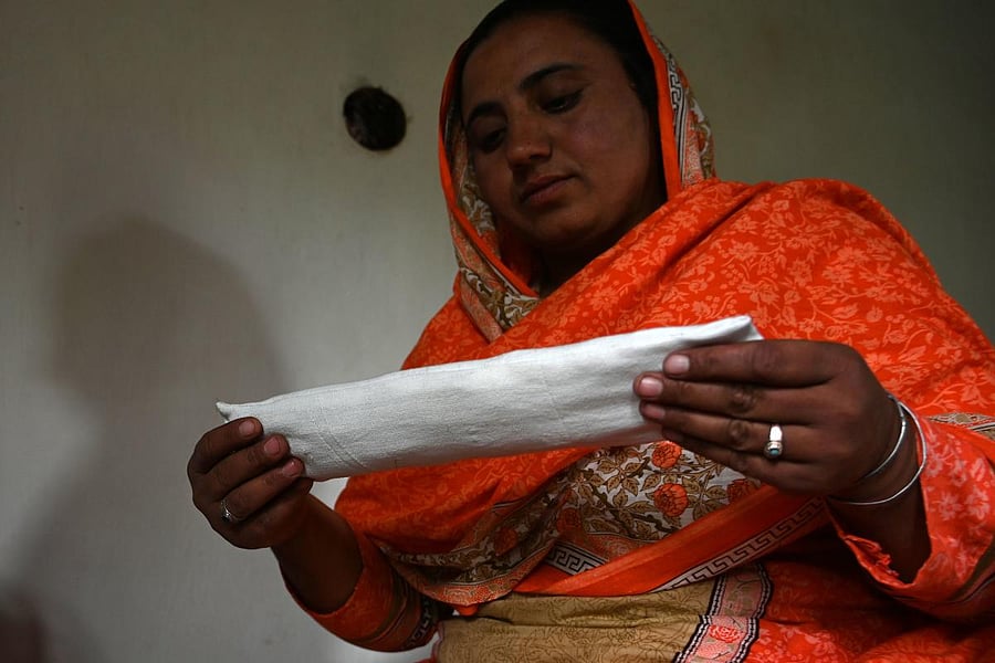 In this picture taken on May 18, 2019, Pakistani woman Hajra Bibi holds a sanitary pad she is making with a sewing machine at her home in Booni village in Chitral. AFP Photo