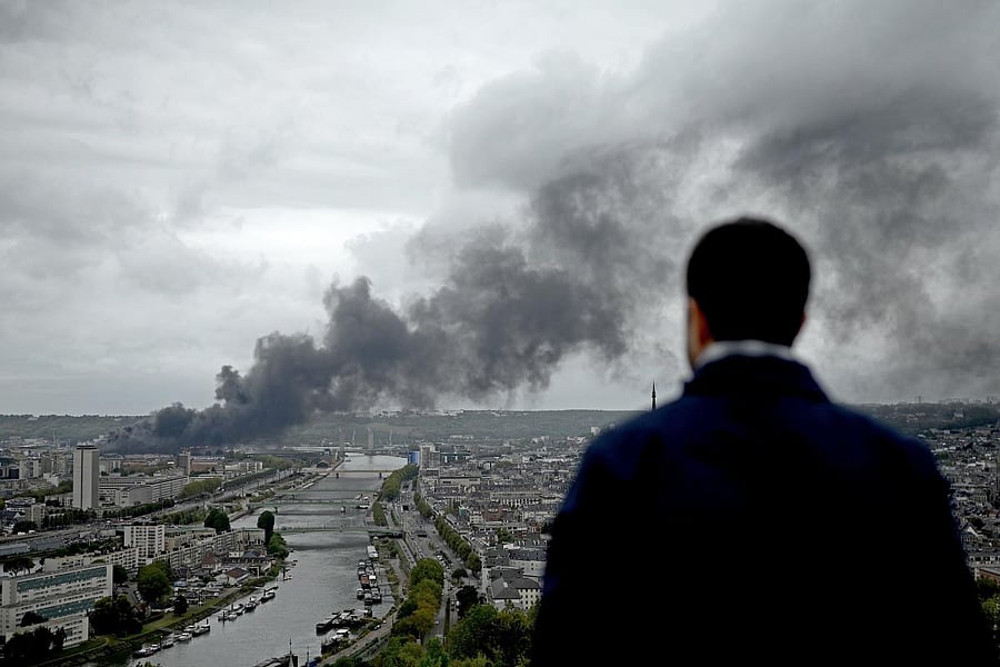 A man looks at smoke billowing from a Seveso classified Lubrizol factory on fire in Rouen, northwestern France. - Residents of twelve towns including Rouen have been asked to stay at home after a fire broke out at a Lubrizol factory classified Seveso high-threshold site, according to the prefect of Normandy. AFP