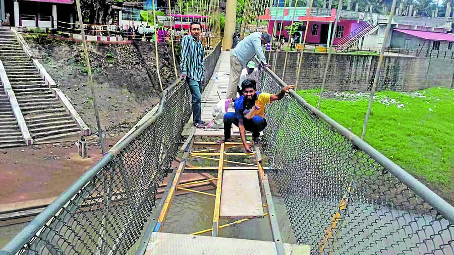 Workers repair the hanging bridge at Kanive village near Kushalnagar.