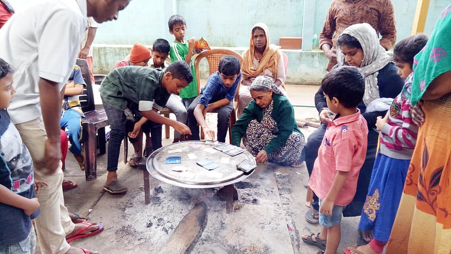 Students help the inmates in drying off the drenched documents at the relief centre in Government Higher Primary School in Nelyahudikeri.
