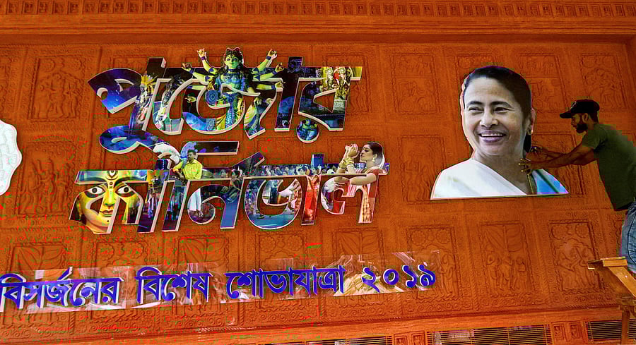 A workers sets up a poster of West Bengal Chief Minister Mamata Banerjee on the eve of Durga Puja Carnival at Red Road in Kolkata, Thursday, Oct. 10, 2019. (PTI Photo)