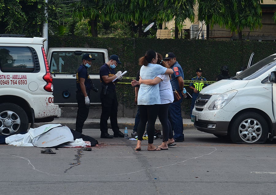 Relatives (R) of slain Clarin town mayor David Navarro mourn next to his body after he and his police escort were ambushed in Cebu. (AFP Photo)