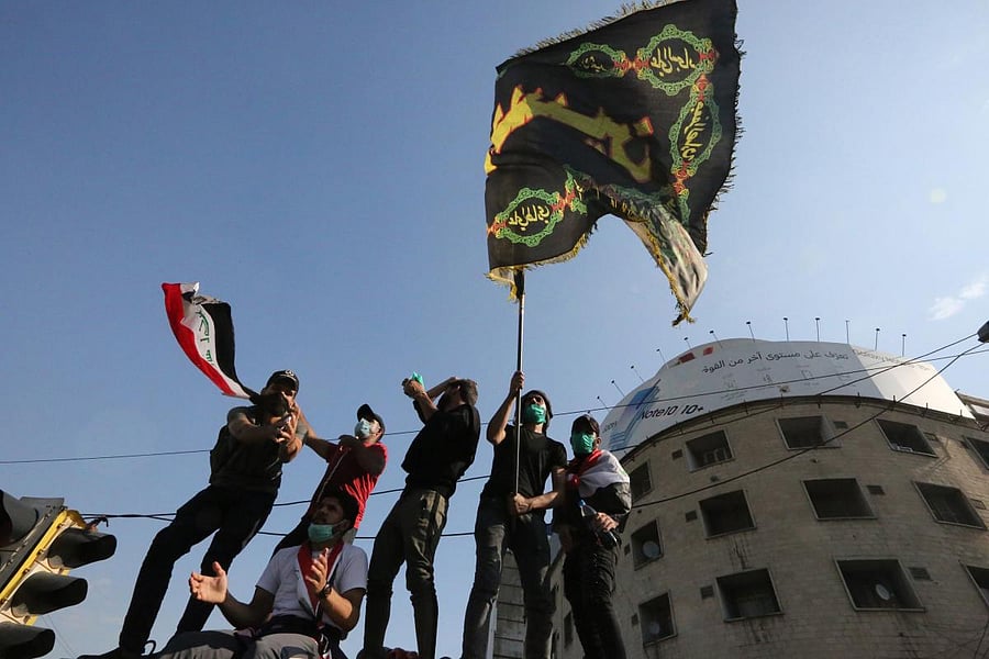Iraqis demonstrators wave a national (L) and another bearing the words "O Hussein" in Arabic, referring to the prophet Mohamed's grandson Imam Hussein ibn Ali, in the capital Baghdad's Tahrir square. AFP