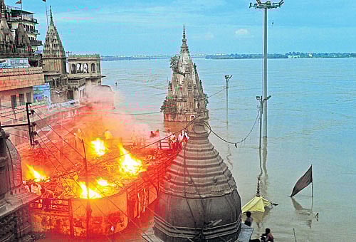 in distress: People hold a cremation ceremony on the roof of a building in Varanasi on Tuesday. Varanasi has been forced to halt cremations along the banks of the river Ganga following floods, an official said. AFP