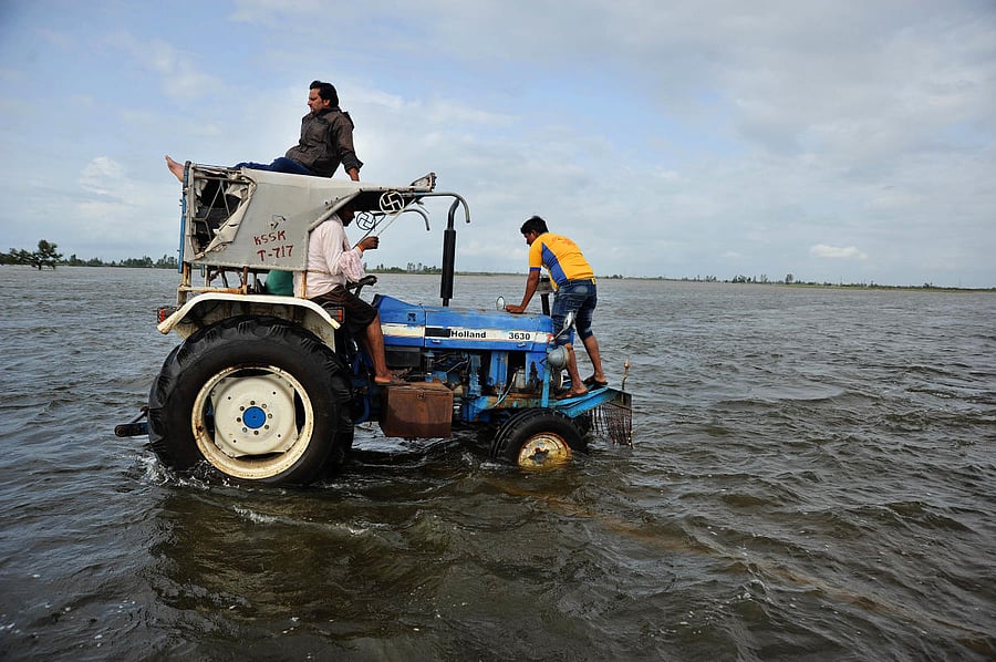 A tractor navigates on an inundated road 5 km away from to the fully submerged Darur village in Athani taluk of Belagavi district. Finding land for the rehabilitation centres to shift the residents of the 21 villages continues to remain a challenge. DH Fi