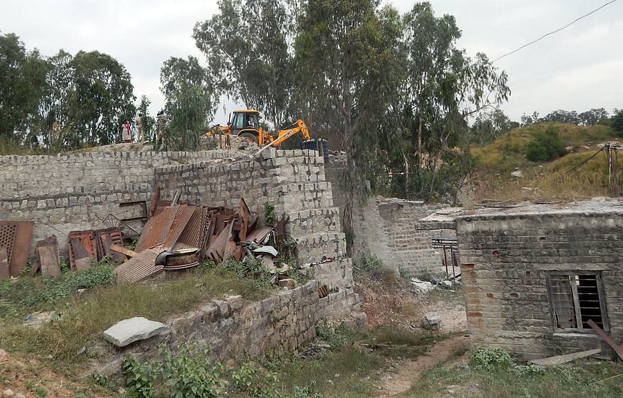 Forest department officials demolish the structures with excavators, at the illegal crushing units in Srirangapatna, Mandya district on Friday.