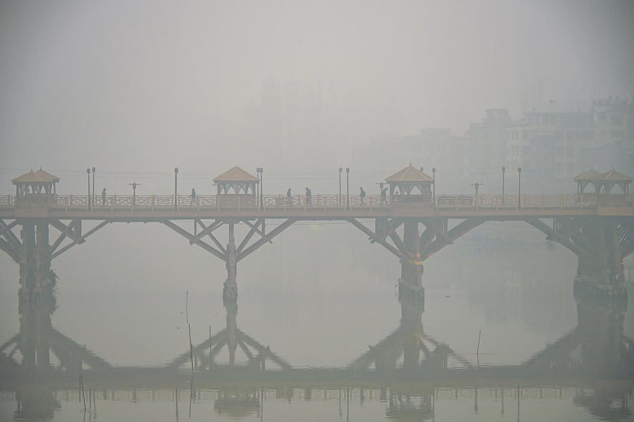 Pedestrians cross a bridge on a cold, foggy morning, in Srinagar. PTI