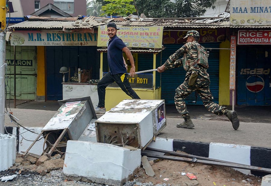 A protestor being chased and baton-charged by a security personnel during an agitation against the Citizenship Amendment Bill, in Guwahati. PTI