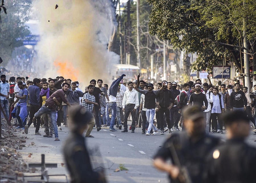 Protestors throw stones as they clash with the police during their march against the Citizenship (Amendment) Bill. Photo by PTI.