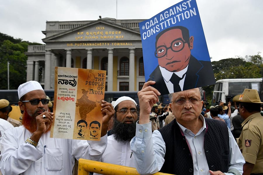 Historian Ramchandra Guha (R) holds a placard against India's new citizenship law during a protest held in spite of a curfew in Bangalore on December 19, 2019.