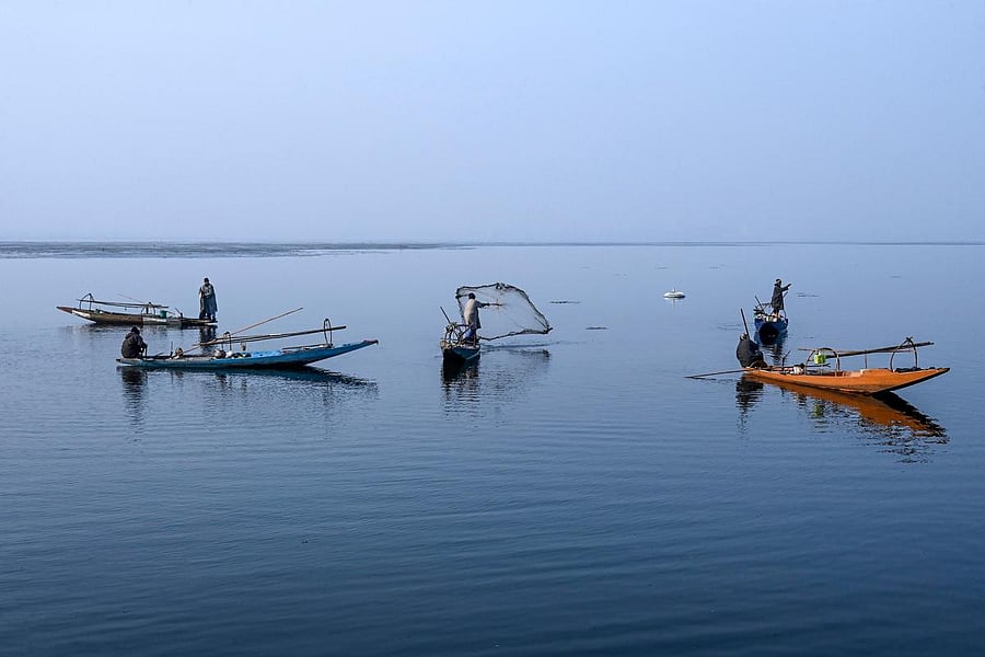 A fisherman (C) throws a fishing net in the Dal Lake during a cold day in Srinagar on December 29, 2019. (AFP Photo)