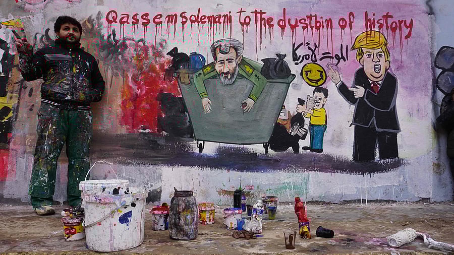 Aziz Asmar, one of two Syrian painters who completed a mural on January 3, 2020 following the killing of Iranian Revolutionary Guards commander Qasem Soleimani poses next to his creation in the rebel-held Syrian town of Dana in the northwestern province of Idlib. (AFP Photo)