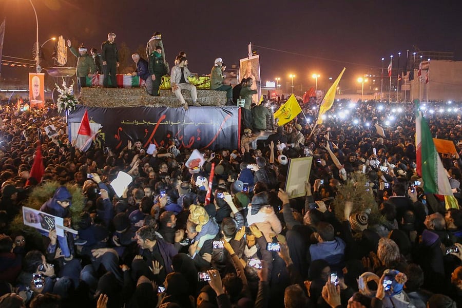 Iranians gather around a vehicle carrying the caskets of slain military commander Qasem Soleimani and others during a funeral procession after the bodies arrived in the northeastern city of Qom on January 6, 2020 following a ceremony in the capital Tehran