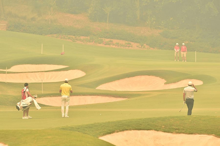 Australian golfer Damien Jordan (C) and New Zealand golfer Ryan Chisnall (R) are seen on the fairway through the thick haze from bushfires at the 1st hole on day one of the Australian Open golf tournament in Sydney. Photo/AFP