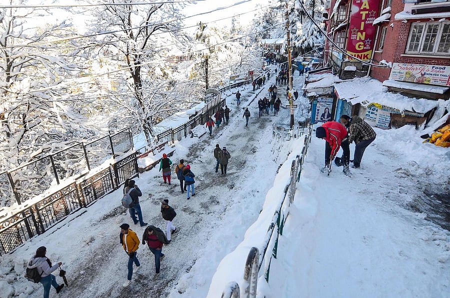 People walk on a snow-covered road after heavy snowfall in Shimla. (PTI Photo)