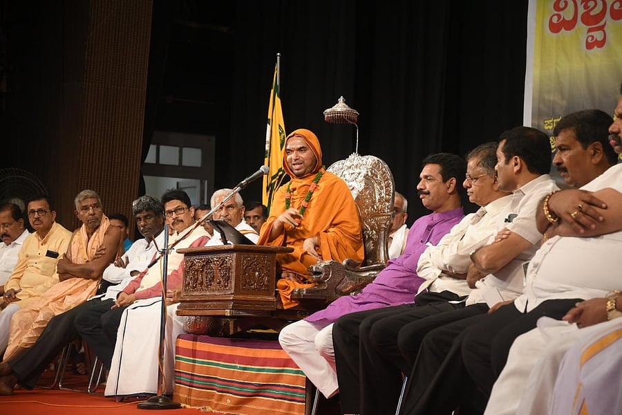 Sri Ramachandrapura Mutt pontiff Raghaveshwara Bharati Swami speaks during an interaction ‘Vishwa Vidya Samvada’ at Town Hall in Mangaluru on Sunday. RSS leader Kalladka Prabhakar Bhat, MP Nalin Kumar Kateel and District In-charge Minister Kota Shrinivas Poojary look on. DH Photo