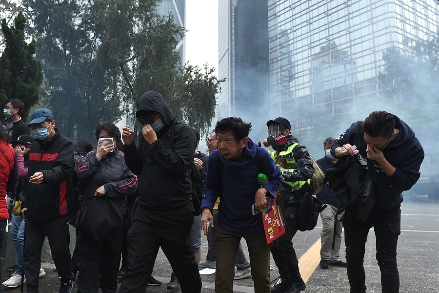 People react from tear gas fired by police to disperse the crowd gathered for the 'universal siege on communists' rally at Chater Garden in Hong Kong. (AFP Photo)