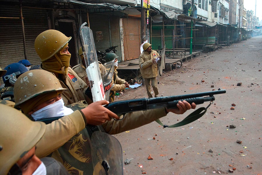 A police personnel aims his gun towards protesters during demonstrations against India's new citizenship law in Kanpur. (AFP Photo)