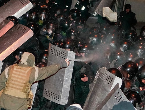 A man sprays gas as Interior Ministry members stand guard during a rally held by supporters of EU integration in Kiev, December 1, 2013. Ukrainian opposition leaders called on Sunday for President Viktor Yanukovich and his government to resign at a rally of about 350,000 people, the biggest protest in the capital Kiev since the 'Orange Revolution' of nine years ago. REUTERS