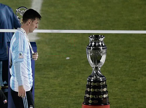 Argentina's Lionel Messi walks next to the Copa America trophy during the Copa America final soccer match at the National Stadium in Santiago, Chile, AP photo
