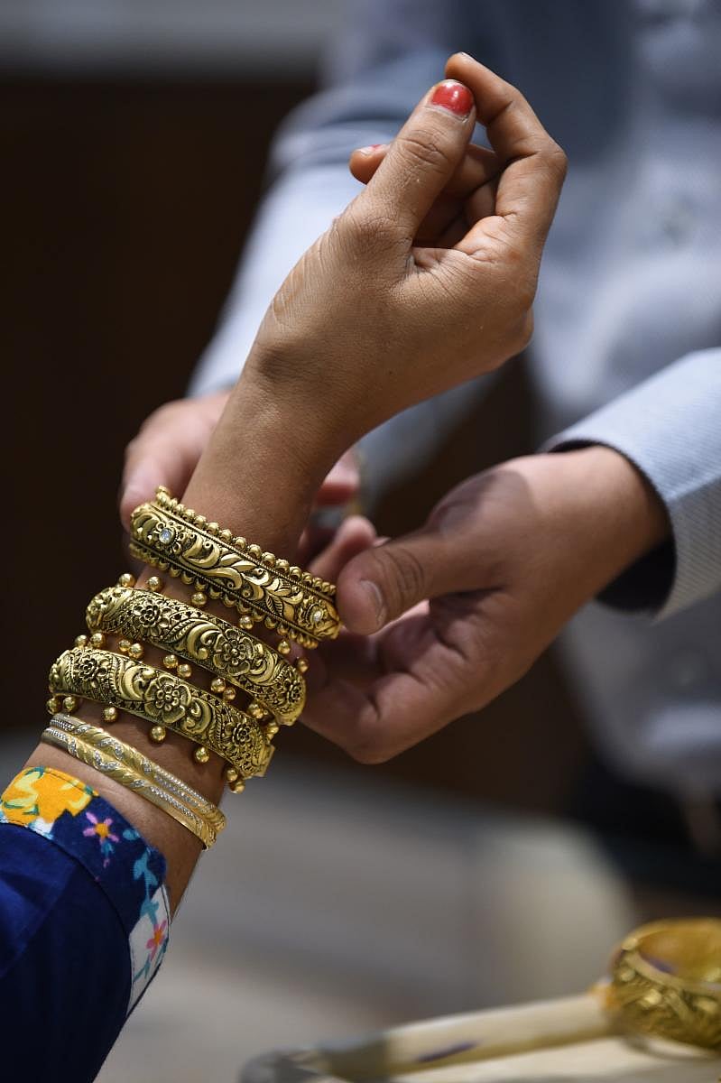 A customer (L) tries a of 22 carat gold engraved bangles at a jewelry shop in Ahmedabad on August 18, 2019. (AFP Photo)