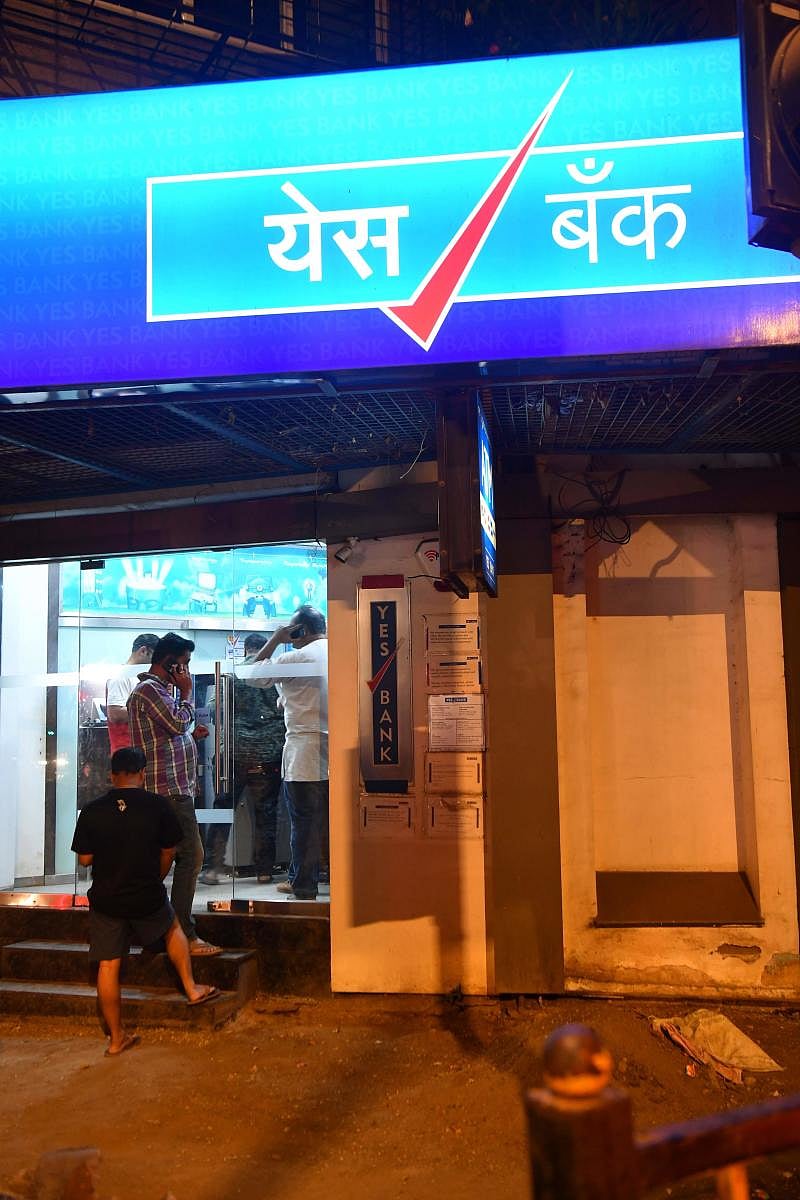 Customers of Yes Bank queue up to withdraw money from their accounts at an ATM (AFP Photo)