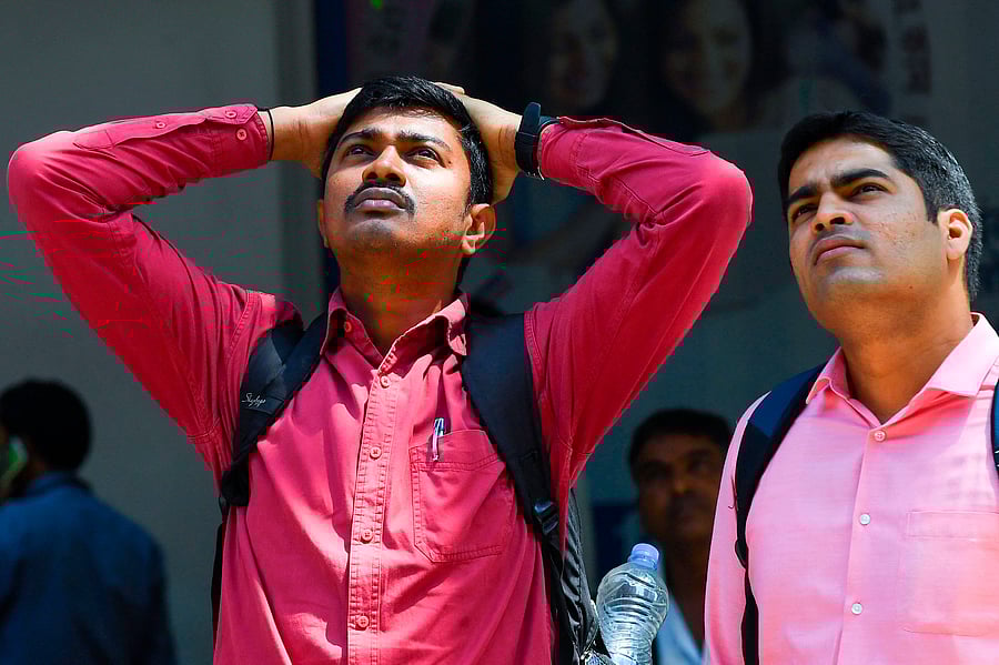 People watch share prices on a digital display on the facade of the Bombay Stock Exchange (BSE), (Credit: PTI) 