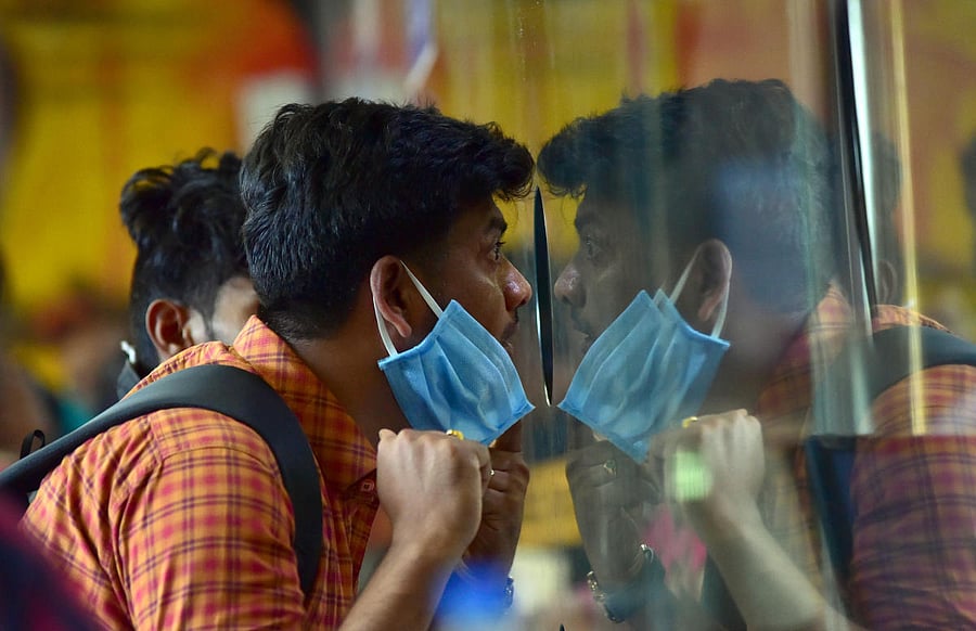 People wearing masks has become a common sight across Bengaluru. A man is seen at a ticket counter at the KSR Bengaluru on Wednesday. DH PHOTO/IRSHAD MAHAMMAD